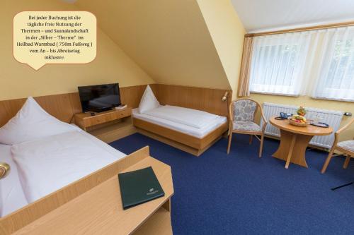 a hotel room with a bed and a table and a tv at Hotel Waldmühle in Wolkenstein