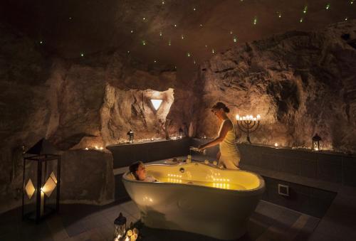 Una mujer parada en una bañera en una cueva en Hotel Restaurant Waldmühle, en Wolkenstein