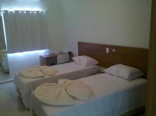 Dos camas en una habitación de hotel con toallas. en Godoy Palace Hotel Ltda Me, en Presidente Prudente