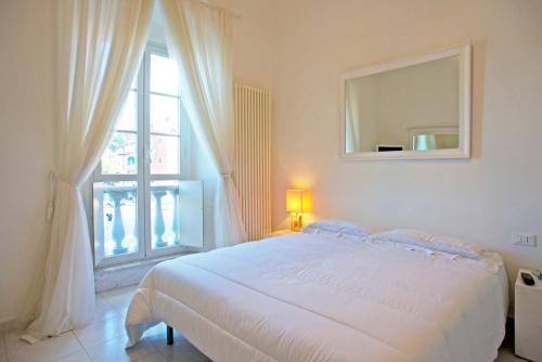 a white bedroom with a large bed and a window at Vittoria in Lerici