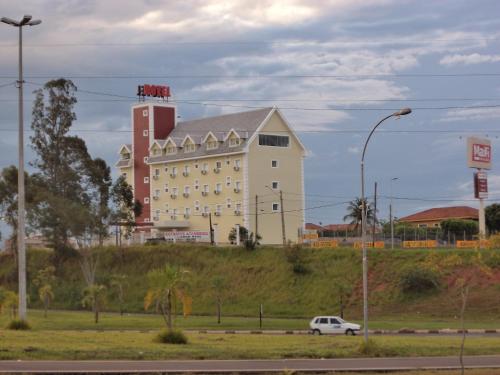 um carro branco estacionado em frente a um grande edifício em Godoy Palace Hotel Ltda Me em Presidente Prudente