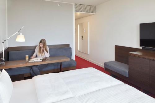 a woman sitting at a table in a hotel room at Empire Riverside Hotel in Hamburg