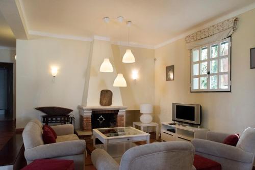 a living room with couches and a tv at Casa do Castelo in Santiago do Cacém