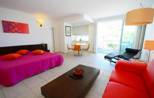 a bedroom with a red bed and a living room at Modern Golden Apartment in Cabanas de Tavira