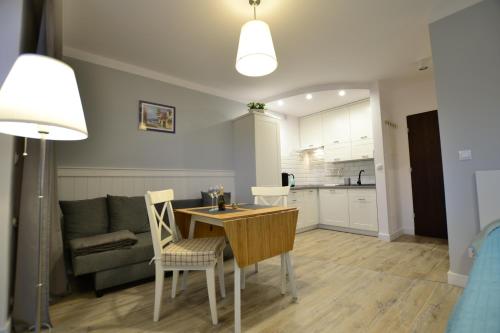 a kitchen and a living room with a table and chairs at Darłówko Apartament Morski VI in Darłówko
