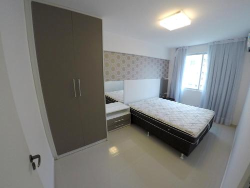 um pequeno quarto com uma cama e um armário grande em A075 - Ed. Mônica, cobertura duplex em Bombinhas
