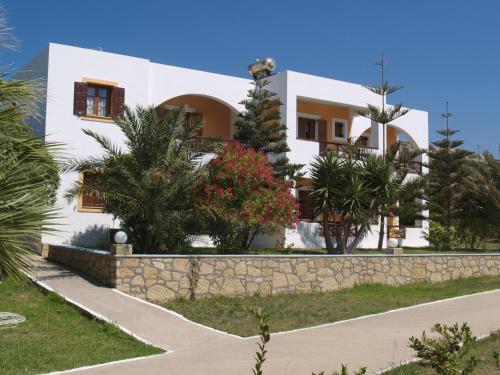 a white house with a stone wall and trees at Saint Nicolas Bungalows in Arkasa