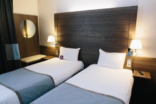 a hotel room with two beds and two lamps at Mercure Mont Saint Michel in Le Mont Saint Michel