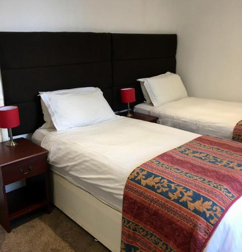 a room with two beds with white sheets and red lamps at Waverley Hotel in Workington