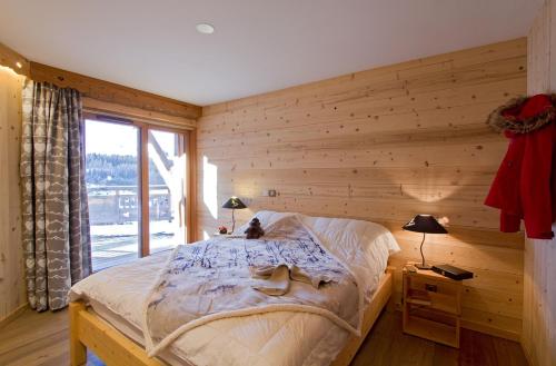 een slaapkamer met een bed met een houten muur bij Odalys Chalet Husky in Les Deux Alpes