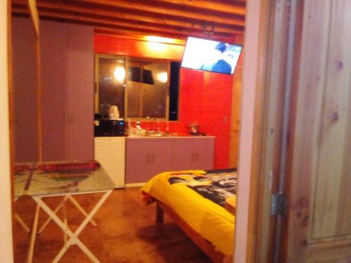 a room with a bed and a kitchen with a tv at Cabañas Mirador de Maitencillo in Maitencillo