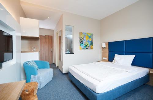 a bedroom with a large bed and a blue chair at Seehotel Kressbronn in Kressbronn am Bodensee
