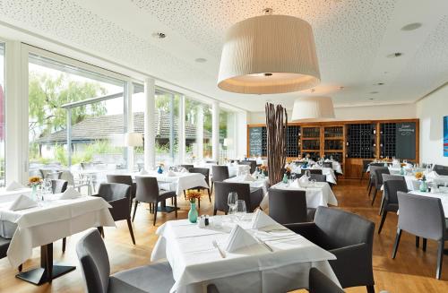 a restaurant with white tables and chairs and windows at Seehotel Kressbronn in Kressbronn am Bodensee