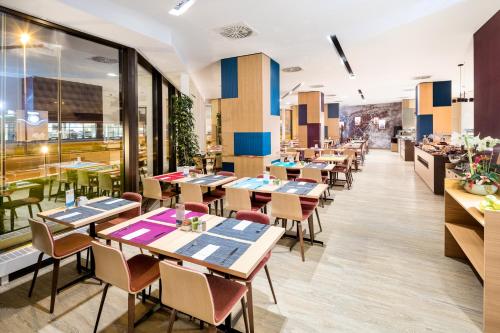 un restaurante con mesas, sillas y ventanas en Occidental Praha, en Praga