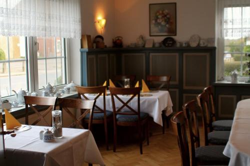 a dining room with two tables and chairs and windows at Karstens Gasthof in Nordhastedt