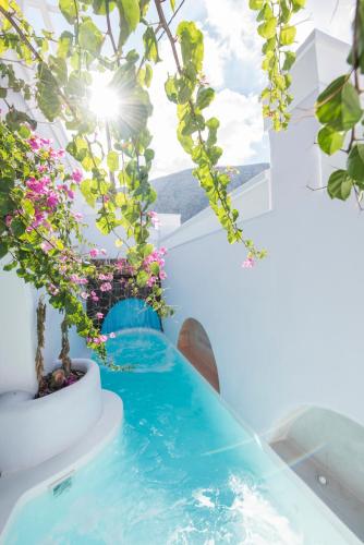 a pool in the middle of a house with flowers at Blue Waves Suites & Apartments in Kamari