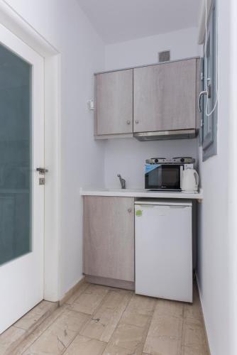 a kitchen with a refrigerator and a microwave at Blue Waves Suites & Apartments in Kamari
