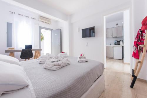 a white bedroom with a bed with towels on it at Blue Waves Suites & Apartments in Kamari