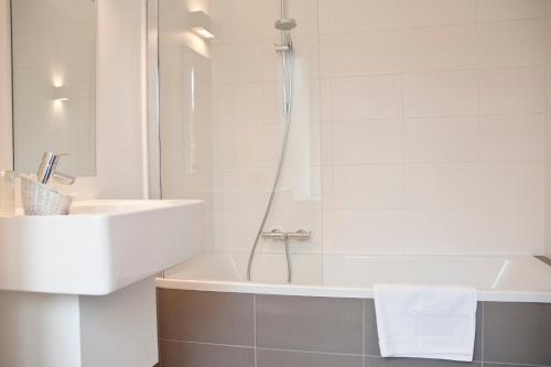 een witte badkamer met een wastafel en een bad bij Domein Martinus in Halle