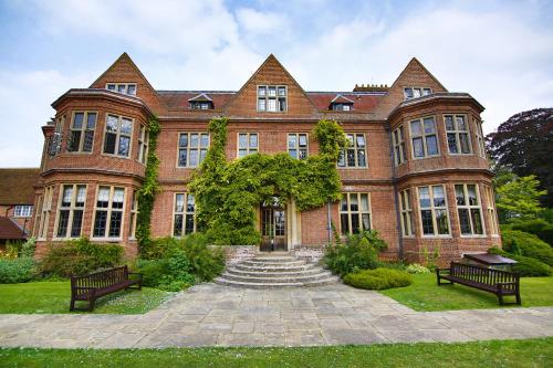 a large brick building with two benches in front of it at Horwood House Hotel in Milton Keynes