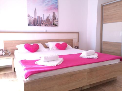 a bedroom with a large bed with two pink pillows at Apartmani Emilio Novalja in Novalja