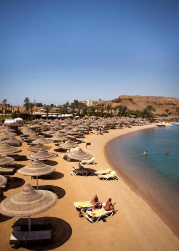 a beach with many umbrellas and people in the water at Xperience Golden Sandy Beach in Sharm El Sheikh