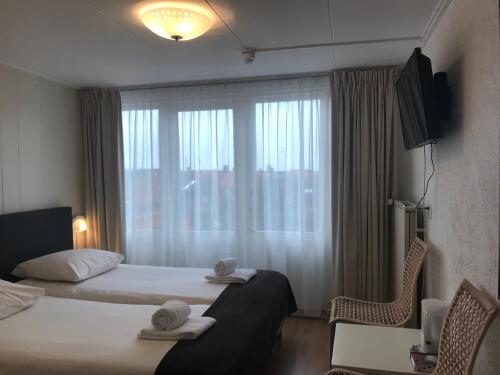 een hotelkamer met 2 bedden en een raam bij Hotel Valkenhof in Zoutelande