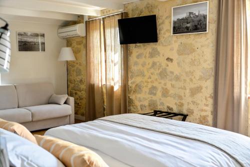 MaignautにあるLogis Hôtel La Ferme de Flaranのベッドとソファ付きのホテルルーム