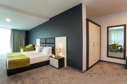 a bedroom with a king sized bed and a mirror at Earth & People Hotel & SPA - Free Parking & Swimming Pool in Sofia