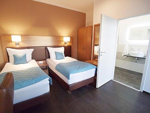 a hotel room with two beds and a bathroom at Sporthotel Dorum in Dorum