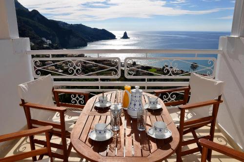 a table on a balcony with a view of the ocean at Mazis Apartments in Agios Gordios