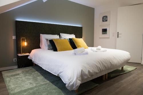 a bedroom with a large white bed with yellow pillows at Luxueux logement Bourgeois de 250 M2 climatisé in Lille