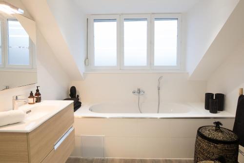 a white bathroom with a tub and two windows at Luxueux logement Bourgeois de 250 M2 climatisé in Lille