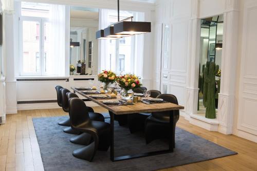 a dining room with a long table and black chairs at Luxueux logement Bourgeois de 250 M2 climatisé in Lille