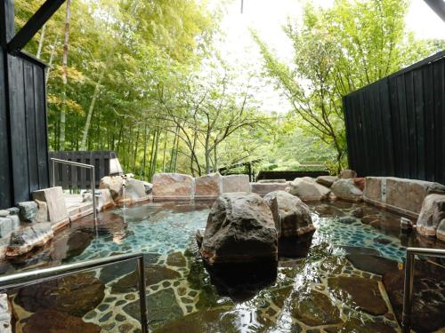 a pool of water with rocks in a yard at 源泉掛け流しの宿Albergo湯楽 in Yugawara