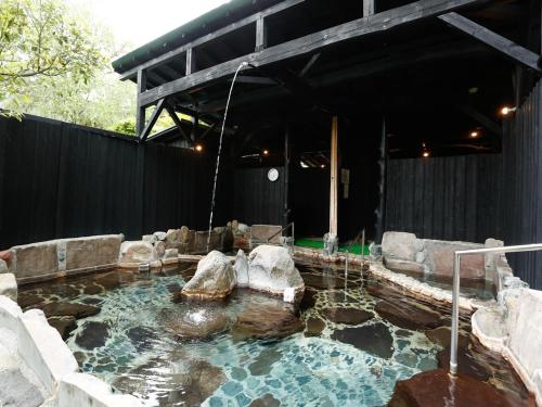 a pool of water with rocks in a backyard at 源泉掛け流しの宿Albergo湯楽 in Yugawara