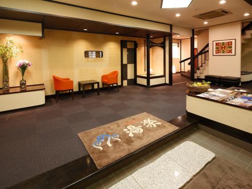 a lobby of a hotel with orange chairs and a rug at 源泉掛け流しの宿Albergo湯楽 in Yugawara