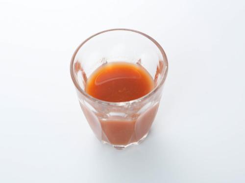 a glass filled with orange liquid on a white background at 源泉掛け流しの宿Albergo湯楽 in Yugawara