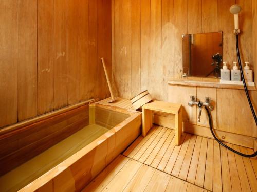 an empty sauna with a tub and a mirror at 源泉掛け流しの宿Albergo湯楽 in Yugawara
