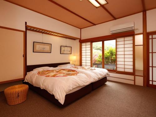 a bedroom with a large bed in a room with windows at 源泉掛け流しの宿Albergo湯楽 in Yugawara