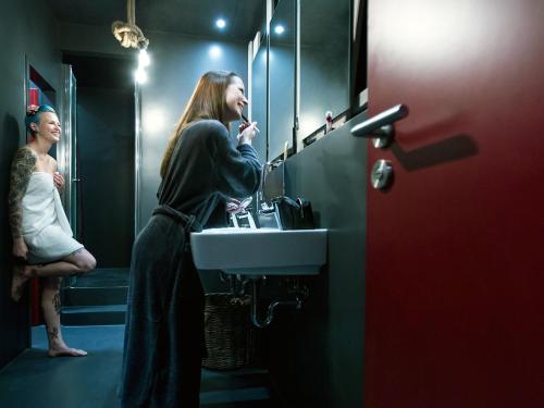 a woman standing in a bathroom brushing her teeth at Heimathafen Hostel in Lörrach