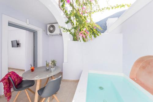 a room with a table and chairs and a tub at Blue Waves Suites & Apartments in Kamari