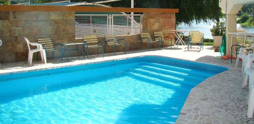 a blue swimming pool with chairs and a table at Hotel Playa in Villa Carlos Paz