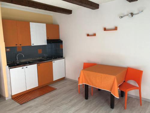 una cocina con mesa y una cocina con armarios naranjas y blancos. en Albergo La Perla, en Craveggia