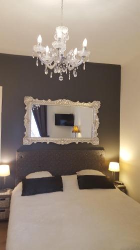 a bedroom with a bed with a mirror and a chandelier at Pension Zee en Duinzicht in Zandvoort