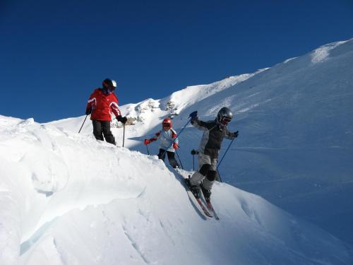 three people are skiing down a snow covered mountain at Pension Appartement Ambrosi in Heiligenblut
