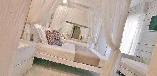 a bedroom with a bed with white curtains and a mirror at Hotel Villa Paola in Rimini