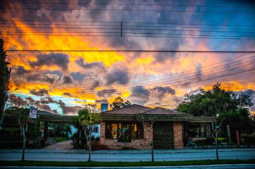 a house with a sunset in the sky at Pousada UpSerra in Urubici