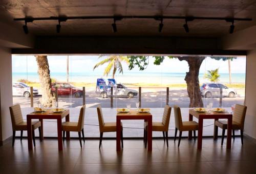 a dining room with tables and chairs and a large window at Hotel do Mar Cabo Branco in João Pessoa