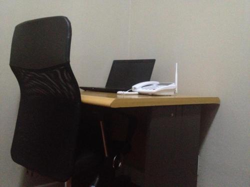 a desk with a black chair and a laptop computer at Angel Guest House in Maputo